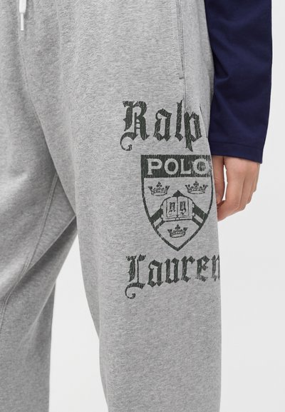 Γκρι φόρμες με μαύρο λογότυπο Ralph Lauren Polo και σήμα τυπωμένο στον μηρό, φορεμένες με μπλε μακρυμάνικη μπλούζα.