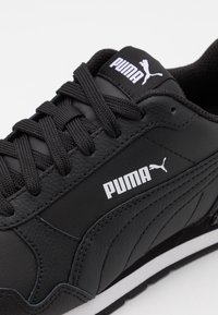 Musta nahkainen lenkkikenkä, jossa on teksturoitu pinta, mustat nauhat ja valkoinen Puma-logo sivussa sekä kielekkeessä, valkoisella taustalla.