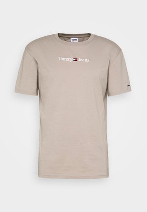 Beige Baumwoll-T-Shirt mit Rundhalsausschnitt. Vorderseite zeigt das "Tommy Jeans"-Logo in Weiß, ergänzt durch ein kleines Logo am Ärmel. Einfaches Design.