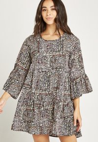 Vestido con estampado floral en negro, rosa y blanco, con mangas acampanadas de tres cuartos, escote redondo y un diseño de falda en capas.