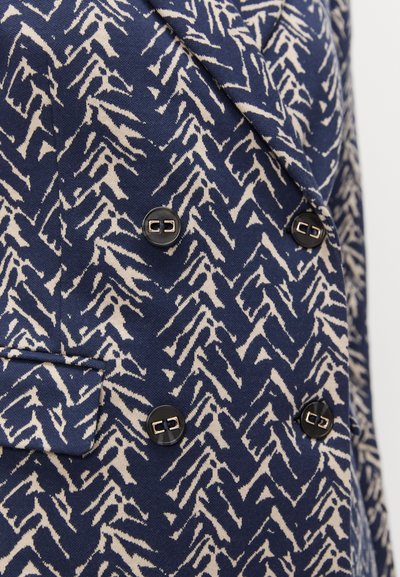 Blazer bleumarin cu un print texturat în crem, cu dublu rând de nasturi, prevăzut cu două nasturi negri și un singur buzunar pe piept.