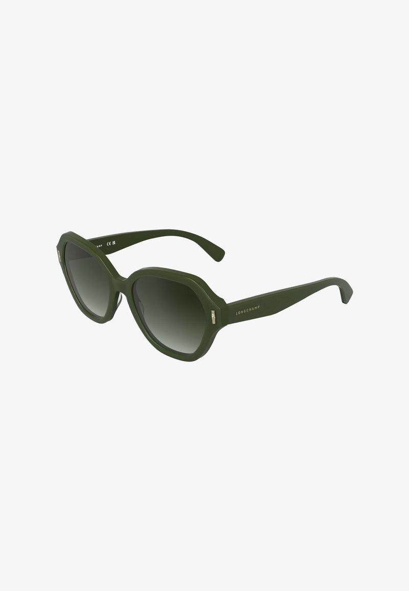Lunettes de soleil vert olive avec des montures octogonales surdimensionnées et des verres dégradés. Accents métalliques sur les branches. Finition mate avec une texture lisse.