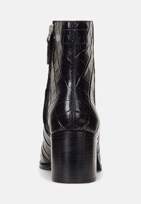 Stivale alla caviglia nero con motivo coccodrillo, design strutturato, hardware della cerniera in argento e tacco spesso e lucido.