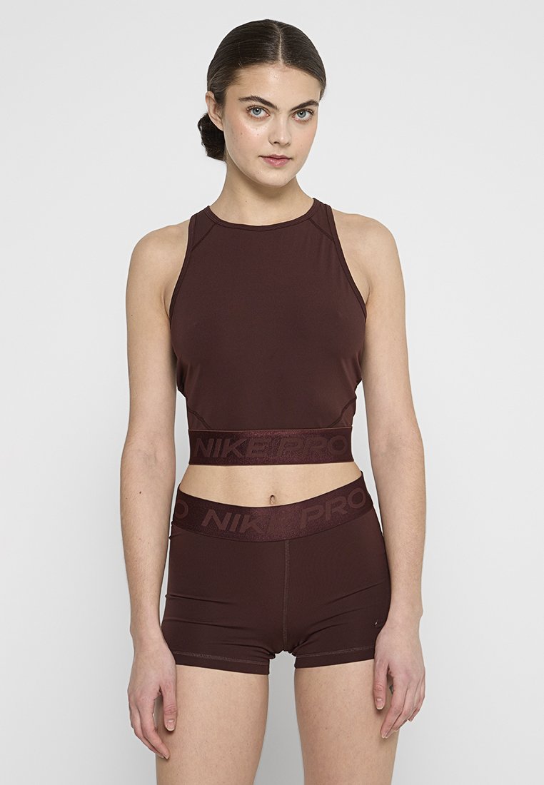 Crop top de sport bordeaux avec un col montant et une taille NIKER PRO. Porté avec un short assorti, en tissu lisse et à la coupe ajustée.