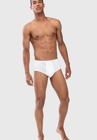 Herren Unterhosen aus weißer Baumwolle mit klassischem Design, featuring einen weichen Bund und eine enganliegende Passform, präsentiert an einem männlichen Modell vor einem neutralen Hintergrund.