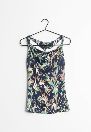 Granatowy, bezrękawnik z kwiatowym nadrukiem w kolorach zielonym, brzoskwiniowym i białym, wiszący na czarnym metalowym wieszaku na białym tle.