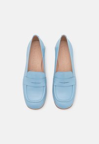 Jasnoniebieskie skórzane mokasyny z zaokrąglonym noskiem, dekoracyjnym przeszyciem i płaską podeszwą. Wnętrze ma subtelny wzór z wytłoczonym napisem "wonder".