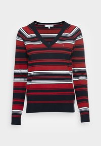 Pull rayé avec des couleurs rouge, bleu marine et blanc, col en V, manches longues, et poignets côtelés avec une finition en tricot texturé.