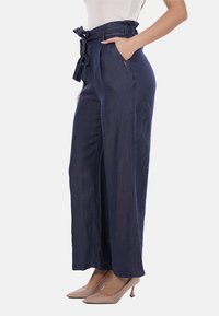 Pantaloni a gamba larga blu scuro con vita alta e tasche frontali, dotati di una cintura abbinata e una texture sottile.