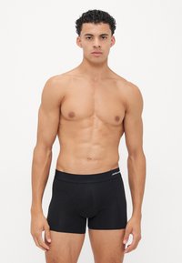 Schwarze Boxershorts aus weichem Stoff, mit einem breiten elastischen Bund und einem Logo. Eng anliegendes Design und minimale Nahtdetails.