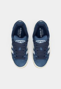 Jūras zila Adidas kedas ar zamša un tekstila virspusi, ar baltām trīs svītrām un gumijas zoli.