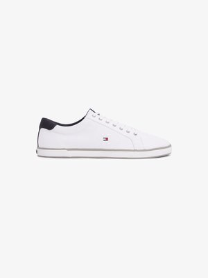 White canvas sneakers with a round toe, gray rubber sole, and black heel accent. Features silver eyelets and a small logo detail on the side.
