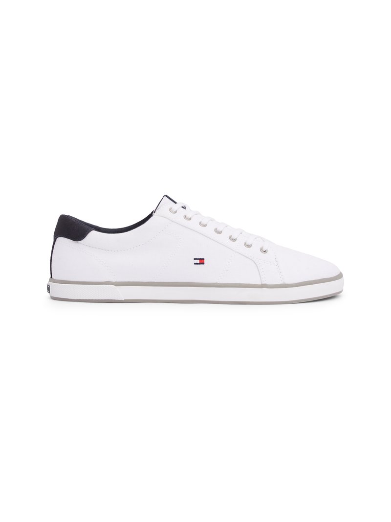 Sneakers bianchi in tela con punta rotonda, suola in gomma grigia e dettaglio nero sul tallone. Presentano occhielli argentati e un piccolo logo sul lato.