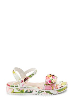 White sandal with floral print, adjustable ankle strap with gold buckle, and ruffled front strap on a thick patterned sole.