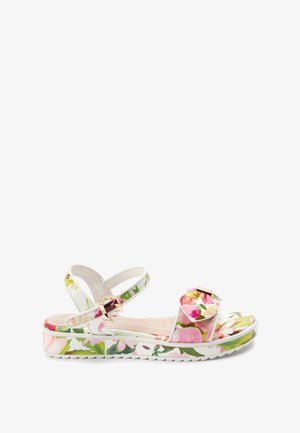 Hvid sandal med blomsterprint, justerbar ankelrem med guldspænde og flæset frontrem på en kraftig, mønstret sål.