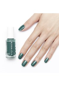 Smalto verde in una bottiglia di vetro etichettata "expressie" accanto a una mano con unghie curate e dipinte dello stesso colore.