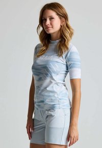 Lichtblauw sporttop met korte mouwen, voorzien van een gestructureerd patroon en hoge halslijn, gecombineerd met bijpassende shorts. Glad stoffen afwerking.