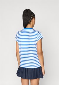 Prugasti kratki rukav majica s plavim i bijelim horizontalnim prugama, s okruglim izrezom i prilagođenim siluetom, u kombinaciji s mornarsko plavom nabranom suknjom.