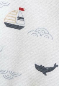 Tela de algodón con un fondo blanco que presenta un velero estampado en beige, negro y rojo, y un delfín negro entre nubes grises.