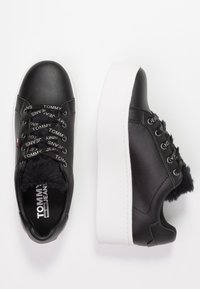 Černé kožené tenisky s bílou platformou, s umělou kožešinou uvnitř a brandovanými tkaničkami. Kulatá špička a polstrovaný límec.