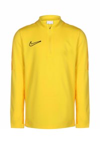 Gelbes Langarmoberteil mit einem Viertel-Reißverschlusskragen. Mit einem schwarzen Nike-Logo auf der Brust und strukturierten orangen Akzenten an den Ärmeln.