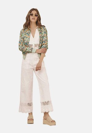 Cárdigan con estampado floral en verde y naranja, mono blanco con escote en V y detalles de encaje, y sandalias de plataforma beige.