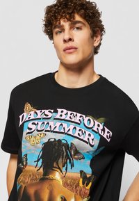 Black cotton t-shirt featuring a colorful graphic with butterflies and a sunset, text reads "DAYS BEFORE SUMMER," crew neck design.