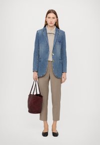 Denim sako s zlatnim gumbima, sivi rebrasti pulover, bež hlače i crvena pletena torba. Crne balerinke. Jednostavan i strukturiran dizajn.