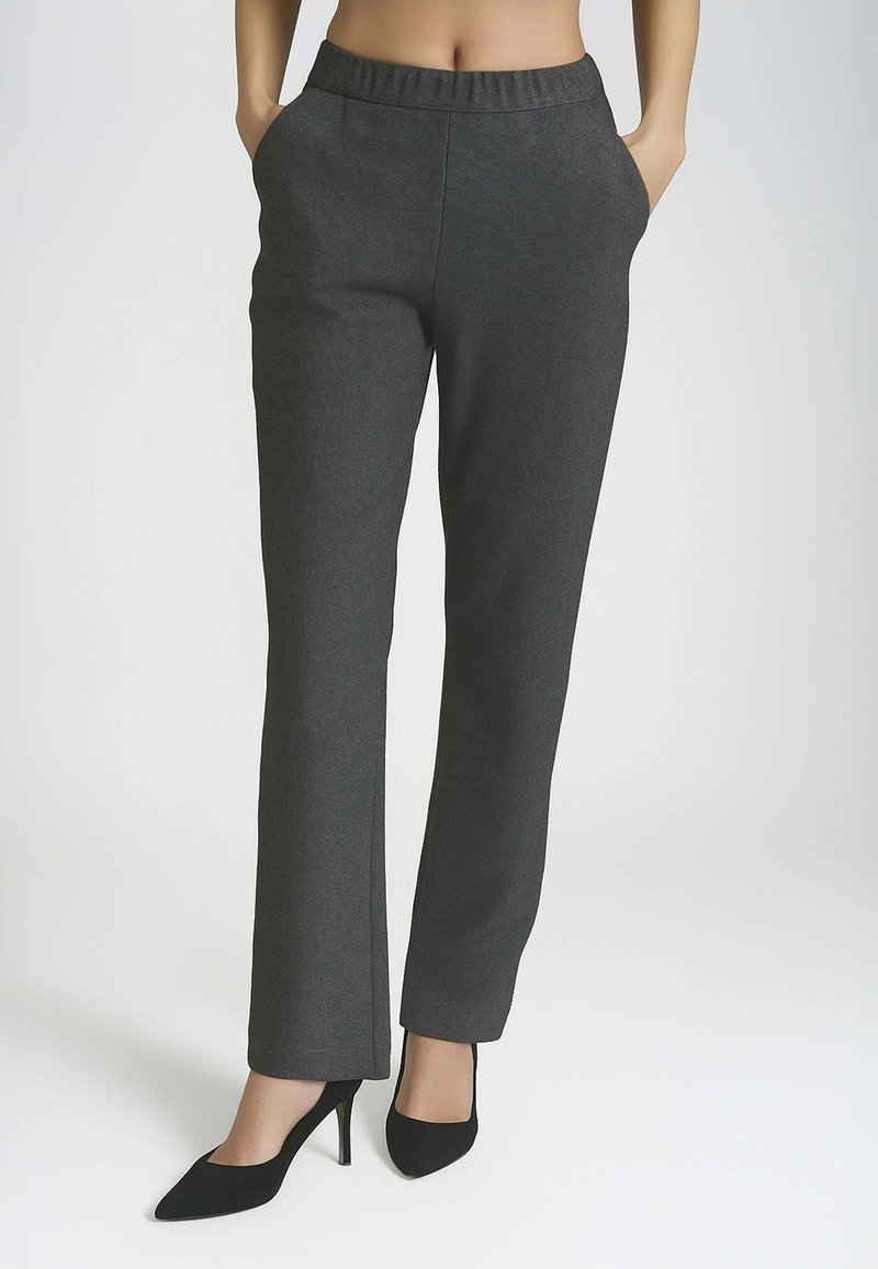 Pantaloni grigi scuri, elasticizzati, con una vita aderente, tasche laterali e un design a gamba dritta. Abbinati a tacchi neri a punta.