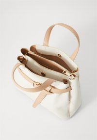 White handbag with light beige straps, a textured surface, and a structured shape. Features a zipper compartment and snap closures inside.
