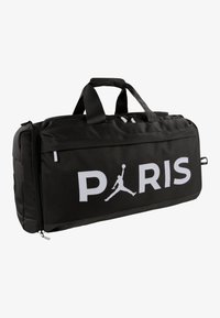 Juodas kelioninis krepšys su baltu užrašu „PARIS“, kuriame yra Jumpman logotipas, patvari medžiaga, užtrauktukais užsegamos kišenės ir dvigubos nešiojimo rankenos.
