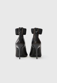 Botine negre cu toc înalt, din piele elegantă, cu închidere cu fermoar și detalii cu bandă elastică la guler. Tocurile stiletto înalte sporesc stilul.