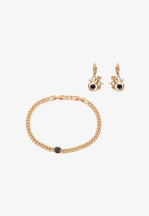 Złota bransoletka na łańcuszku z pojedynczym czarnym kamieniem oraz pasujące złote kolczyki w kształcie kota z czarnymi kamieniami.