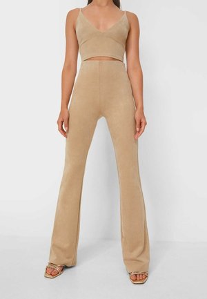 Beige twee-delig outfit met een cropped, mouwloos topje met v-hals en hoge taille, aansluitende wijde broek; zachte textuur en naadloos ontwerp.