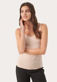 Lichtbeige tanktop met dunne banden, v-hals, gladde textuur en een aangesloten ontwerp, gecombineerd met zwarte broek.
