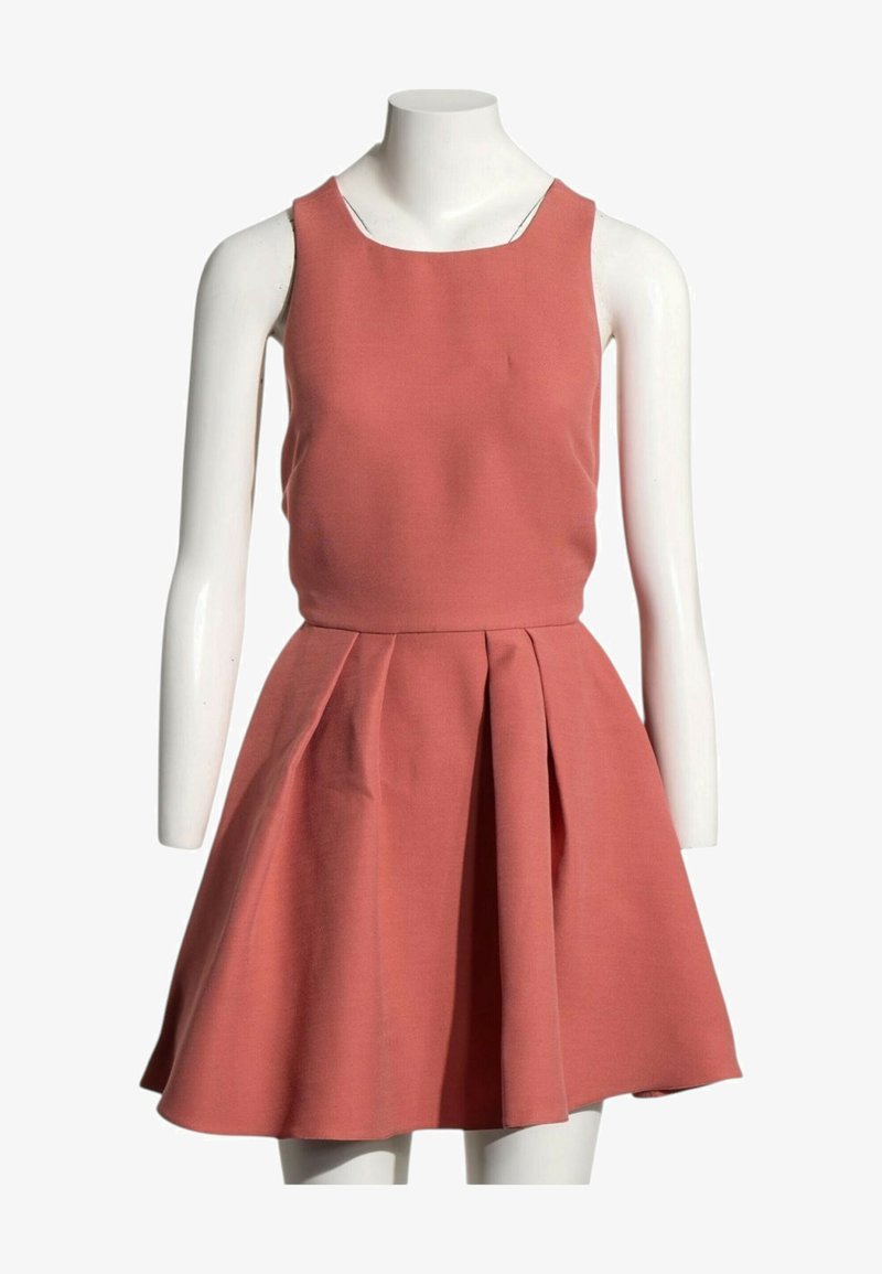Robe rose corail sans manches avec corsage ajusté et jupe évasée plissée, présentée sur un mannequin blanc sur fond blanc.