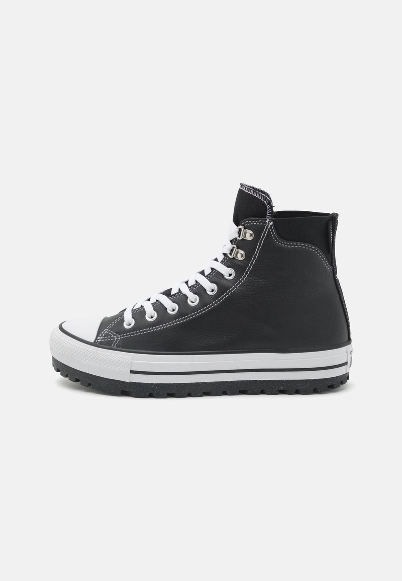 Zapatilla alta de cuero negro con cordones blancos, puntera de goma y suela texturada negra. Presenta costuras blancas en contraste y lazos laterales.