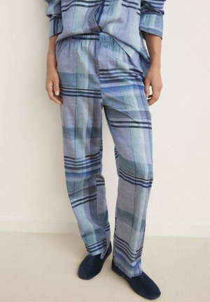Pantalones de pijama ligeros, con un patrón de cuadros en azul y gris, con una cintura elástica. Combinados con zapatillas de casa azul oscuro.