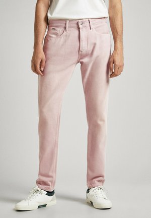 Vaqueros de mezclilla rosa claro con un corte recto, cinco bolsillos y una textura sutil. Combinados con zapatillas blancas con acentos verdes.