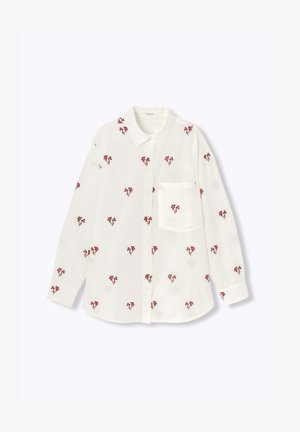 Chemise blanche à boutons avec broderie florale rouge sur l'ensemble, col classique, manches longues et une poche poitrine.