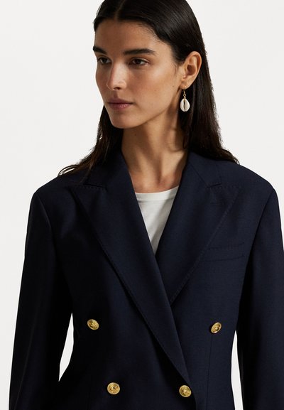 Laivaston kaksirivinen takki, joka on valmistettu sileästä kankaasta ja jossa on kultanapit. Takissa on läpällinen kaulus ja yksi rintatasku.