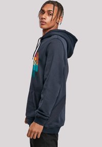 Navy hoodie made of cotton blend, featuring a front pocket, drawstring hood, and a graphic print with mountains in vibrant colors.