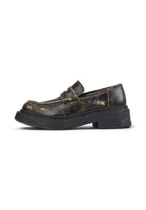 Mocasín de cuero negro con acabado desgastado y suela gruesa y texturizada, mostrado en vista lateral sobre fondo blanco.