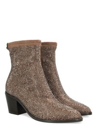 Botas cortas marrones de ante, con un conjunto de tachuelas metálicas, punta afilada y tacón apilado. Parte superior texturizada y costuras decorativas.