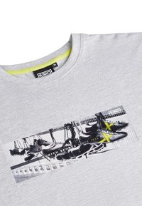 Siva pamučna majica središnjim grafičkim prikazom crnih sportskih tenisica s žutim detaljima. Oznaka glasi "MUNICH SPORTS OD 1939."