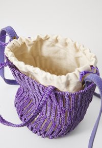 Purple woven bag with a drawstring top, featuring a beige lining and textured, patterned exterior made of durable material.