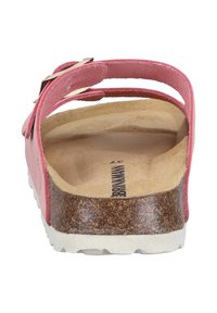 Różowy zamszowy sandał z dwoma regulowanymi paskami, teksturowaną korkową wkładką i białą gumową podeszwą. Widok od tyłu uwydatnia konstrukcję pasków.