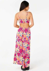 Robe maxi avec motif floral en rose, orange et bleu. Elle présente des bretelles fines, une découpe au dos et une silhouette fluide. Conçue avec une taille froncée.