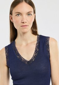 Débardeur bleu marine avec une texture côtelée, doté d'un décolleté en V profond et d'une doublure en dentelle le long de l'encolure et des bretelles.