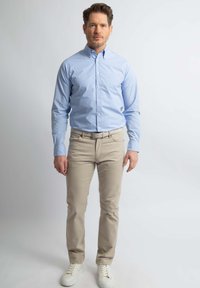 Lichtblauw overhemd met knopen en strepen, beige chinos en witte sneakers. Slank model met een borstzak en casual stijl.
